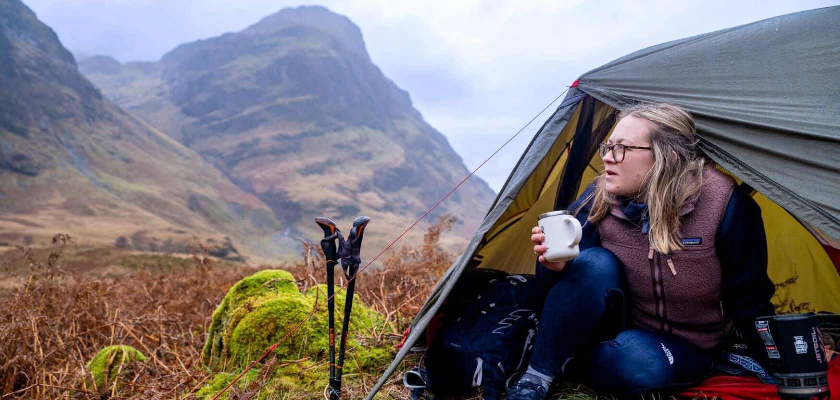 Woman sipping tea in her tent and gazing at the view