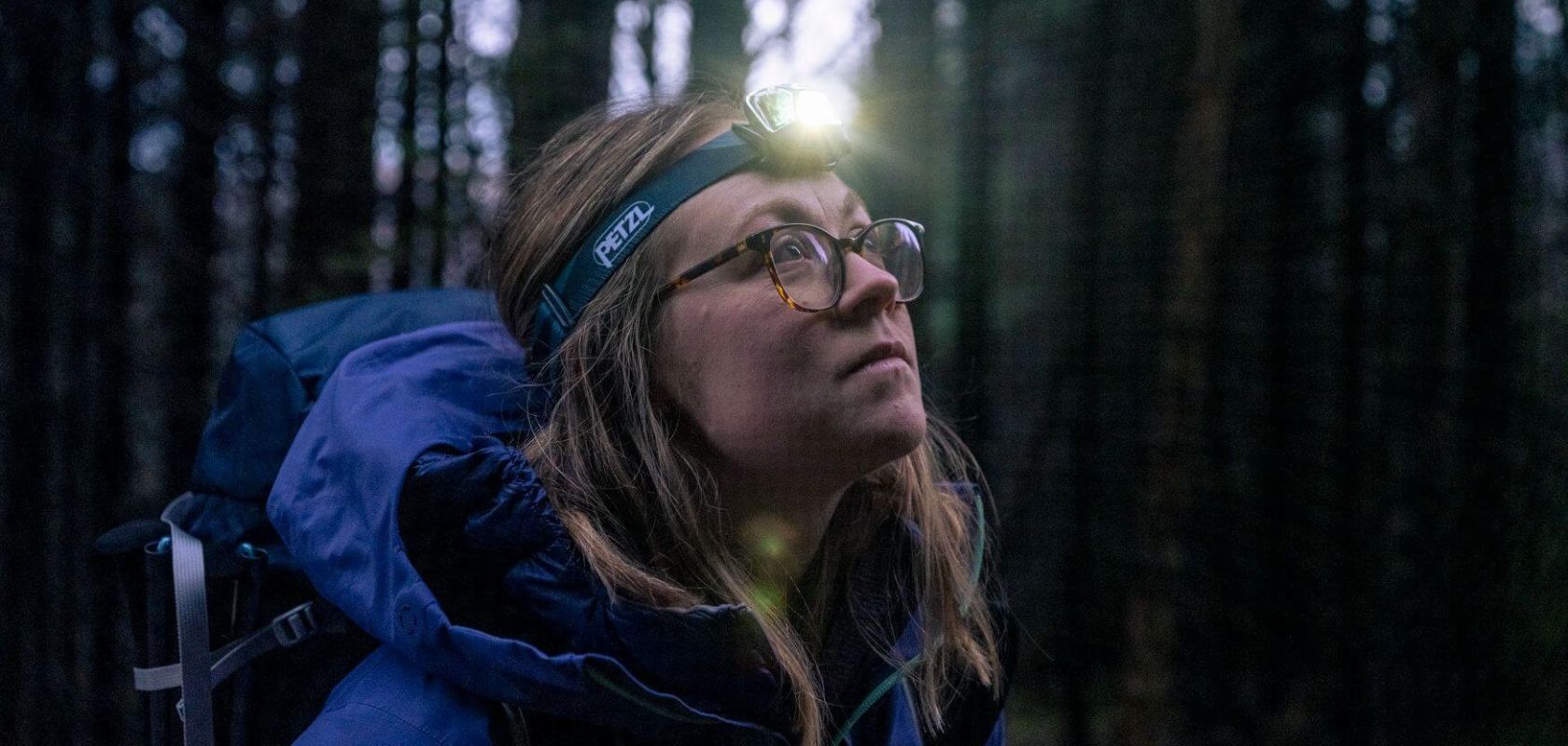 Women wearing a headtorch in the woods