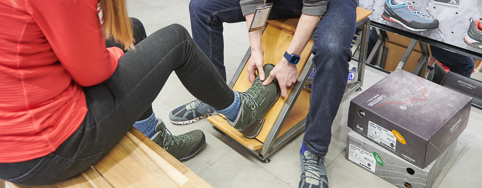 One person is fitting a boot for another in a shop