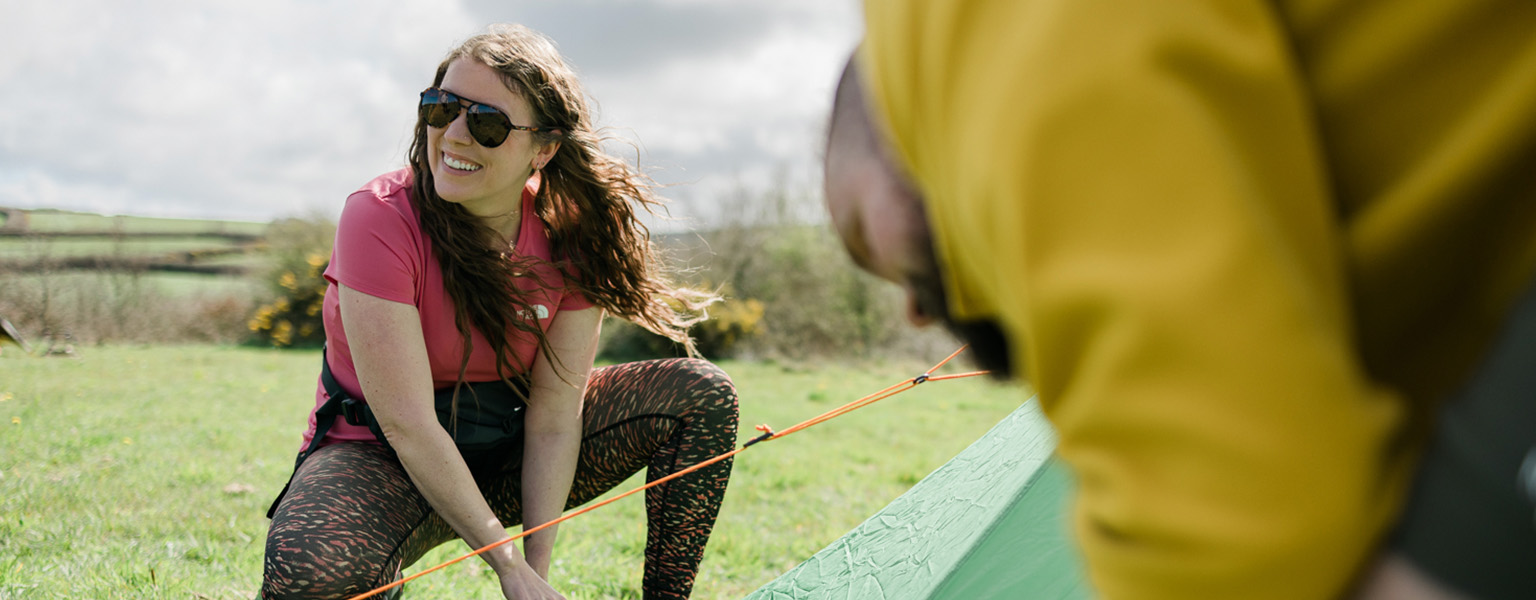 A woman and a man are pitching a tent