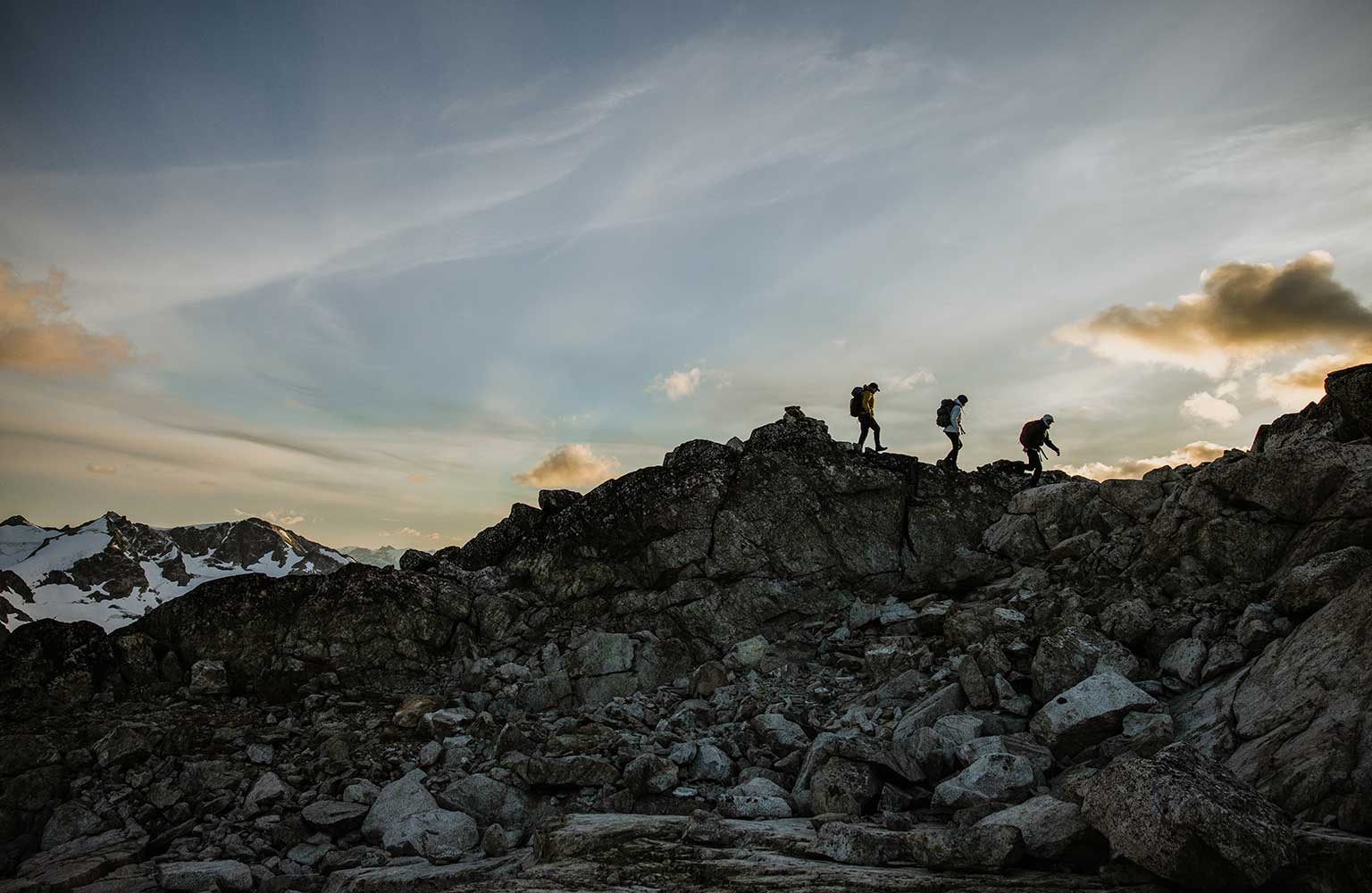 three people climbing a mountain