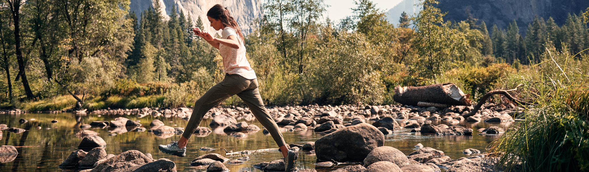 woman walking over rocks in shallow water