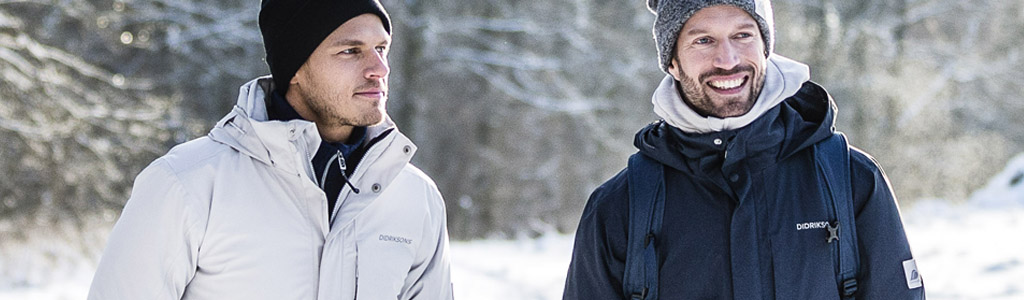 Two men in winter coats and hats on a winter background