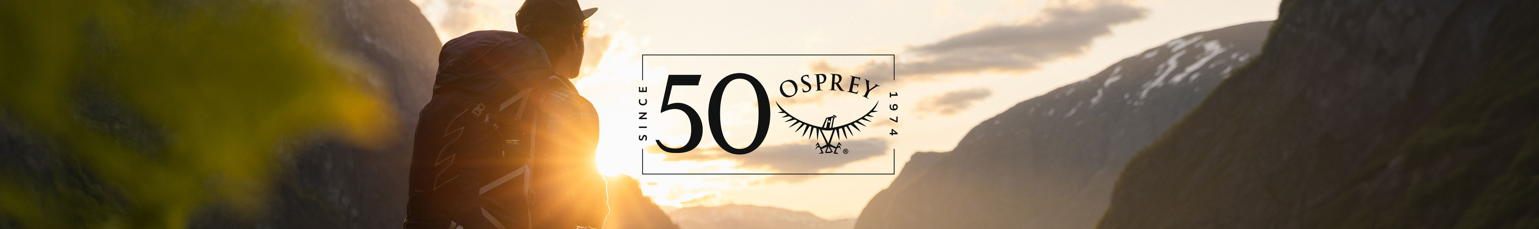 two people walking along mountain with Osprey logo in the middle