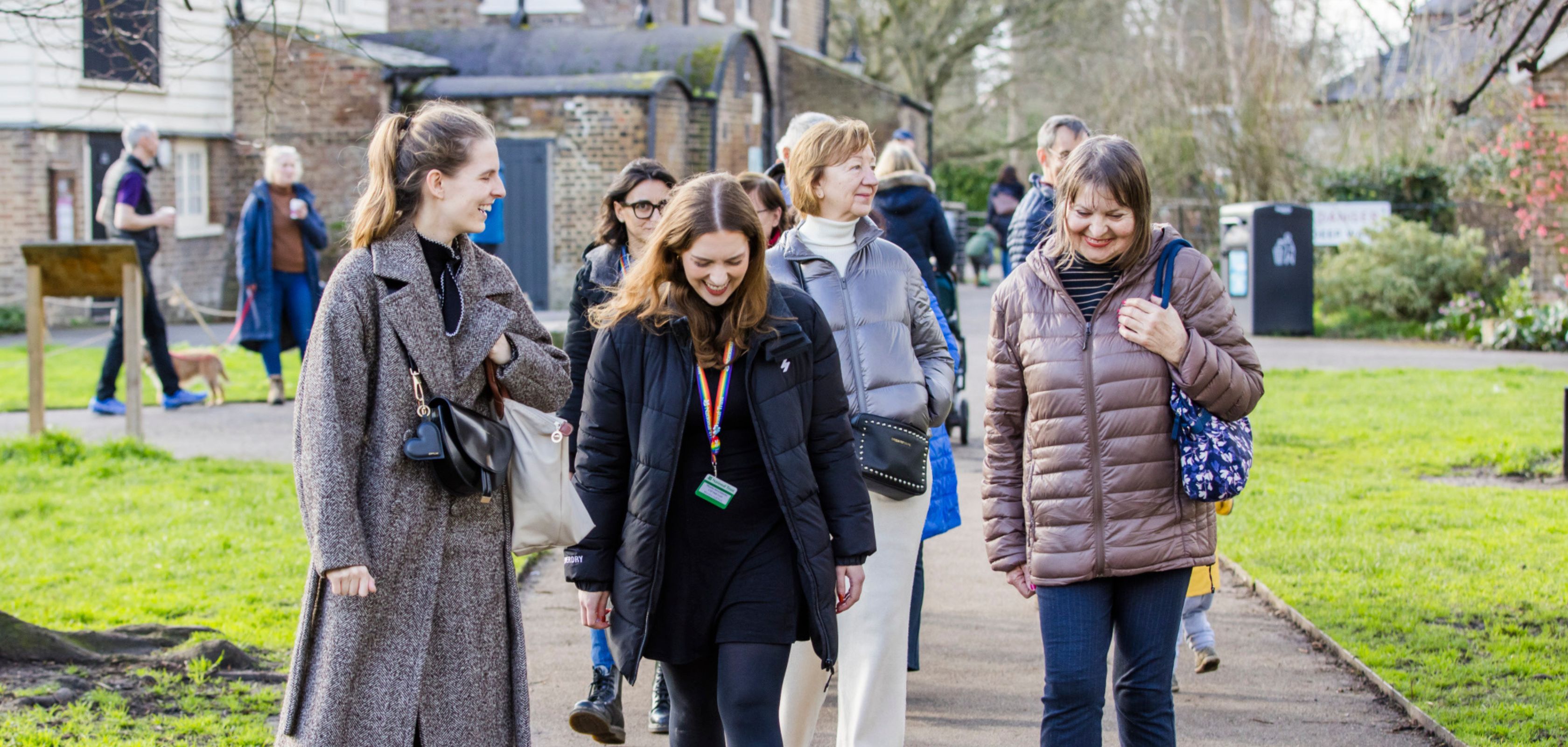 A group of people walking in a local park, smiling and talking