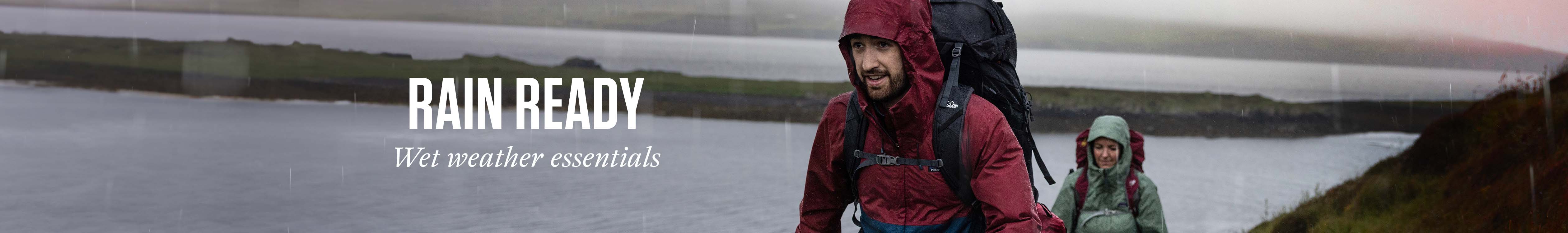 Two people, wearing jackets and rucksacks, are walking in the rain