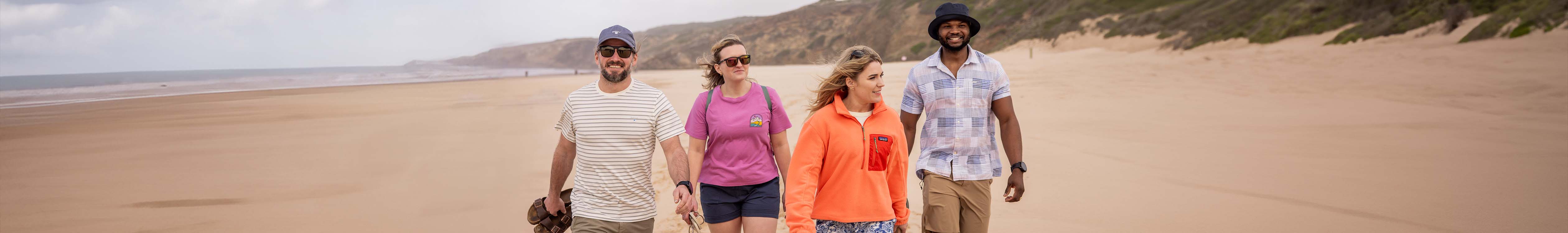 Shop summer clothing. a group of people walking on a beach in summer clothes