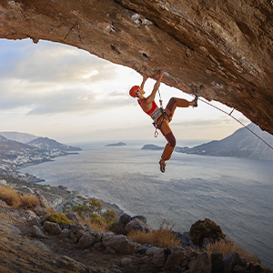 Climber hanging from rock with sea view 