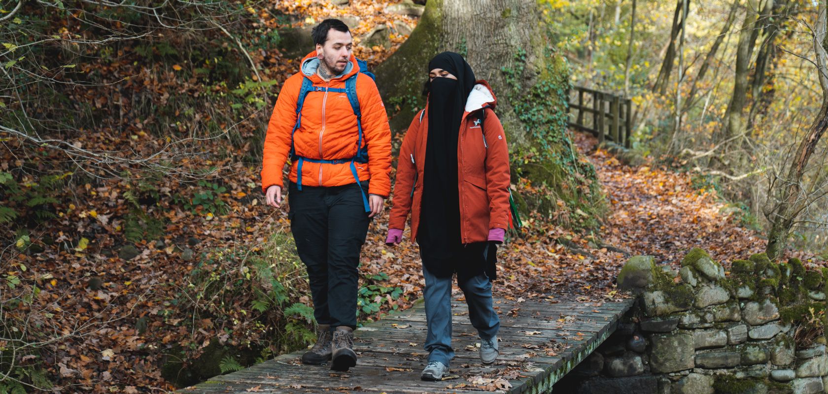 2 hikers crossing a bridge in a woodland