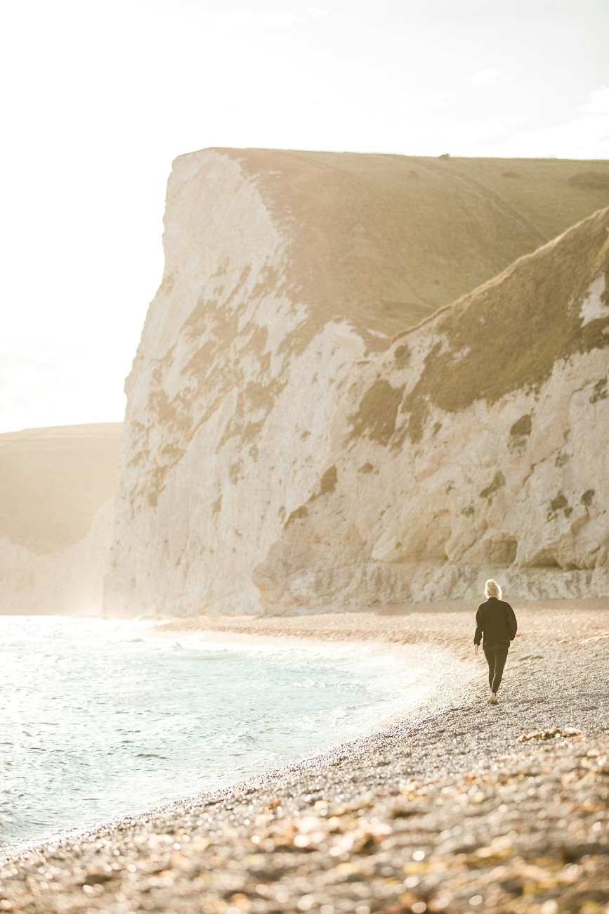 A person walking towards the cliffs on Durdle Door Beach