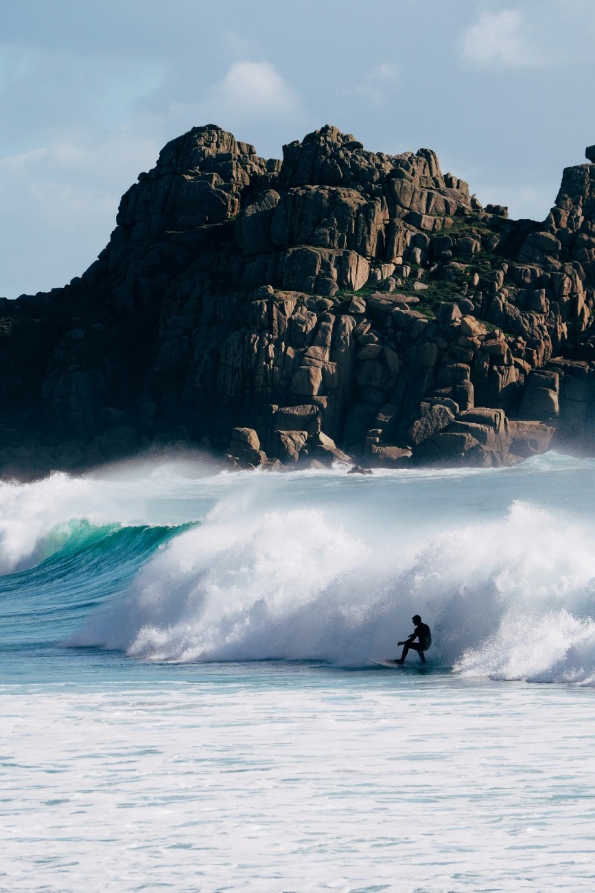 A person surfing the waves at Porthcurno beach