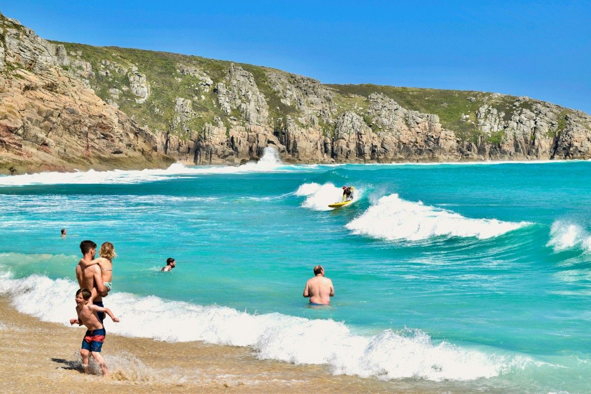 People enjoying the sun and sea at Porthcurno beach