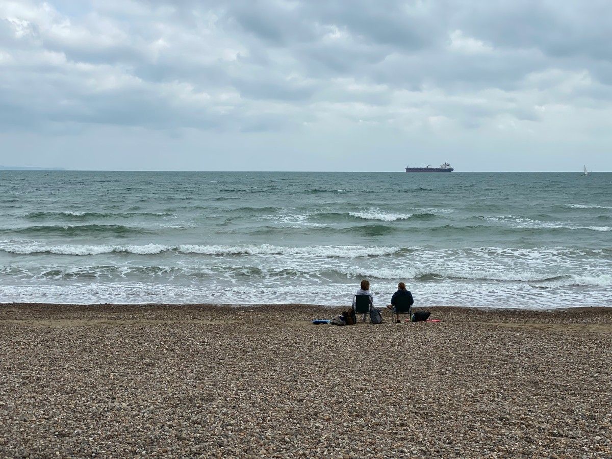 Two people on chairs on a beach in Weymouth