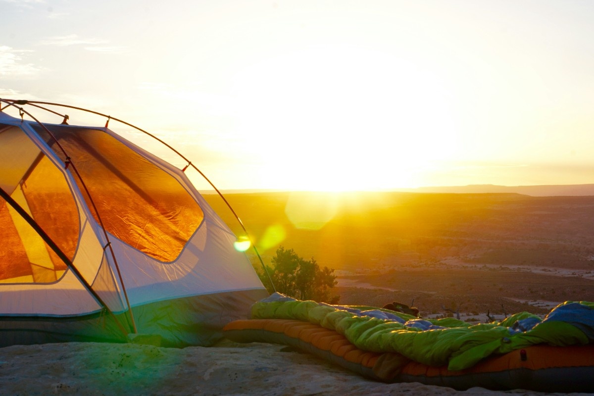 A backpacking tent with the sun setting behind them 