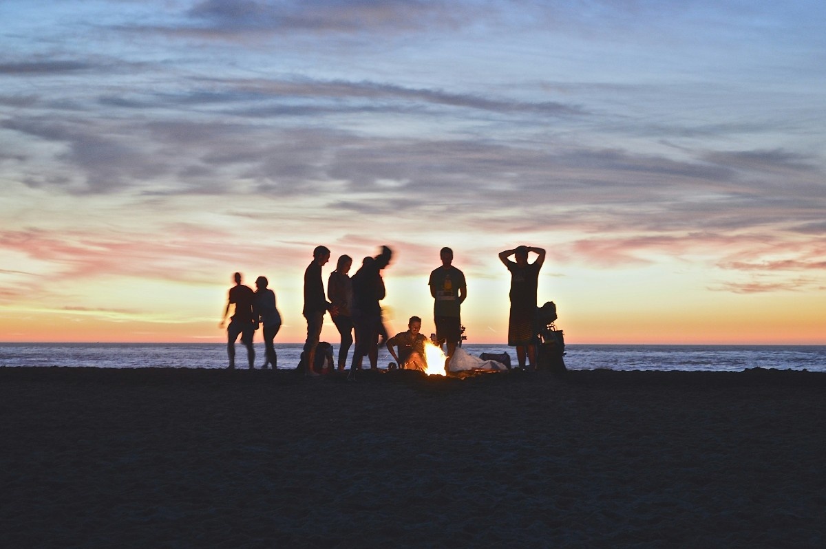 A group of people with a campfire on the beach 