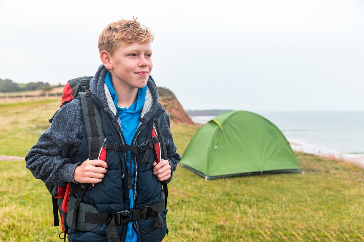 A boy in front of a tent on the coastline 