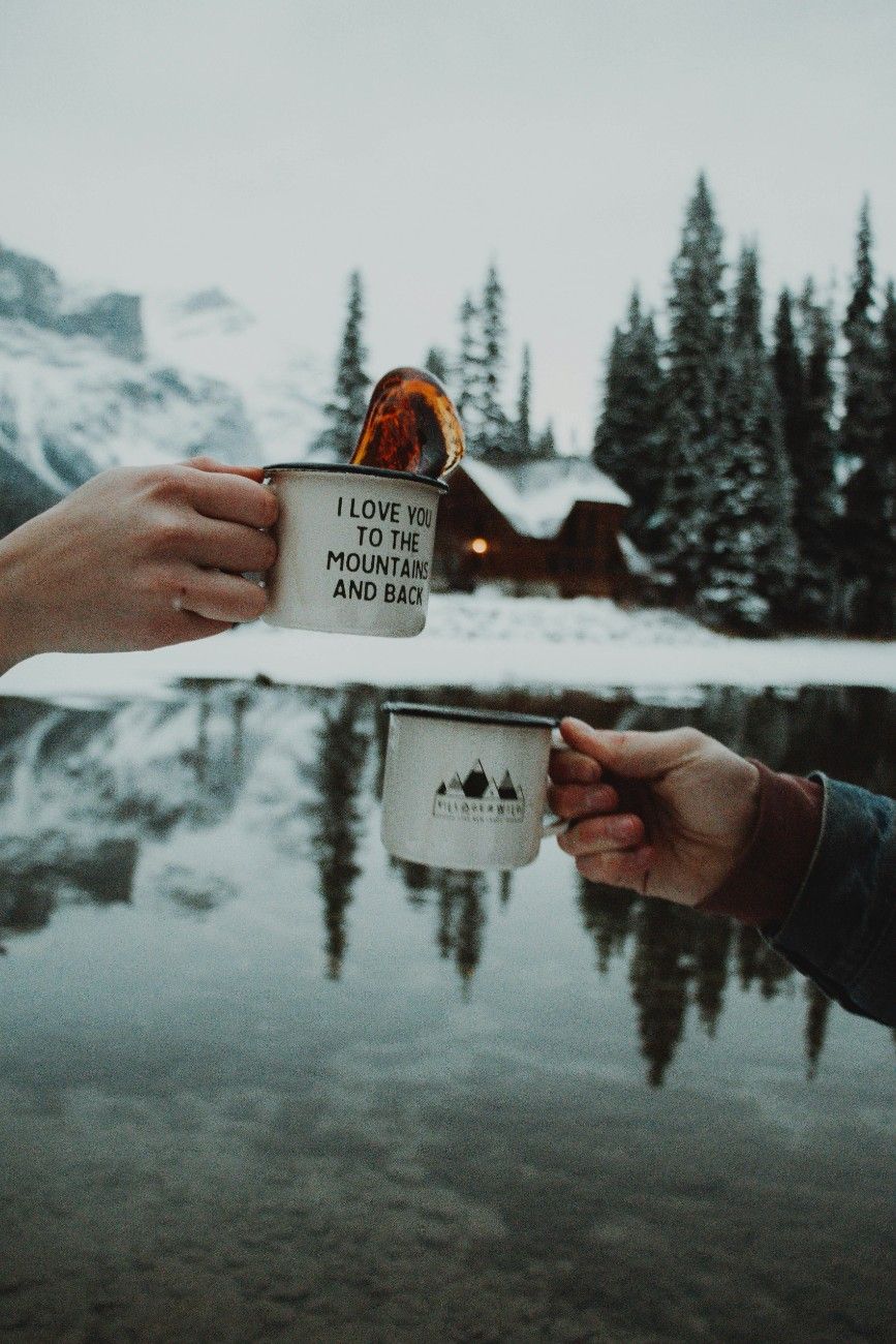 Two people with their camp mugs in the snow 