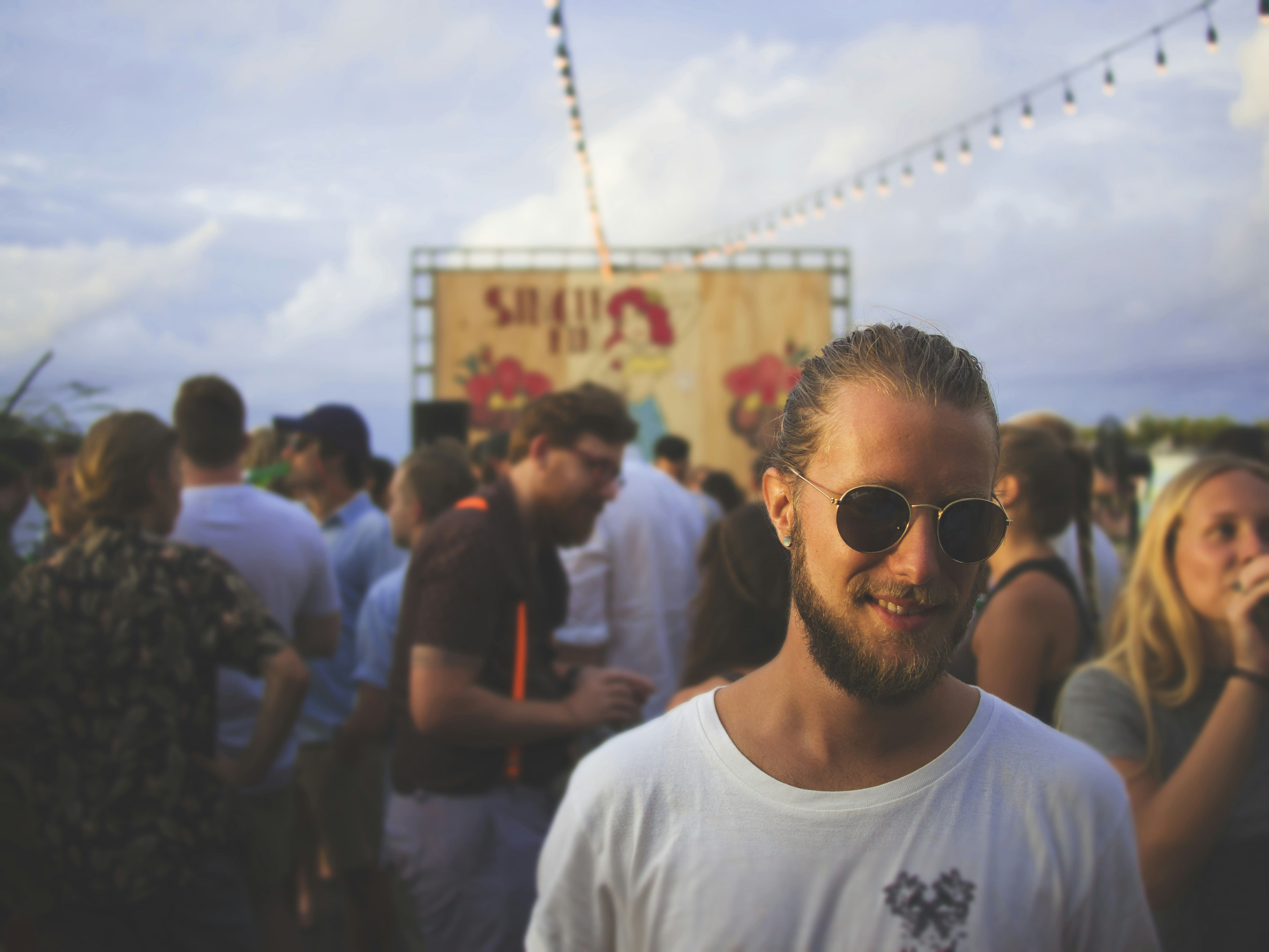 A man stood in front of a stall at the festival, wearing sunglasses and smiling