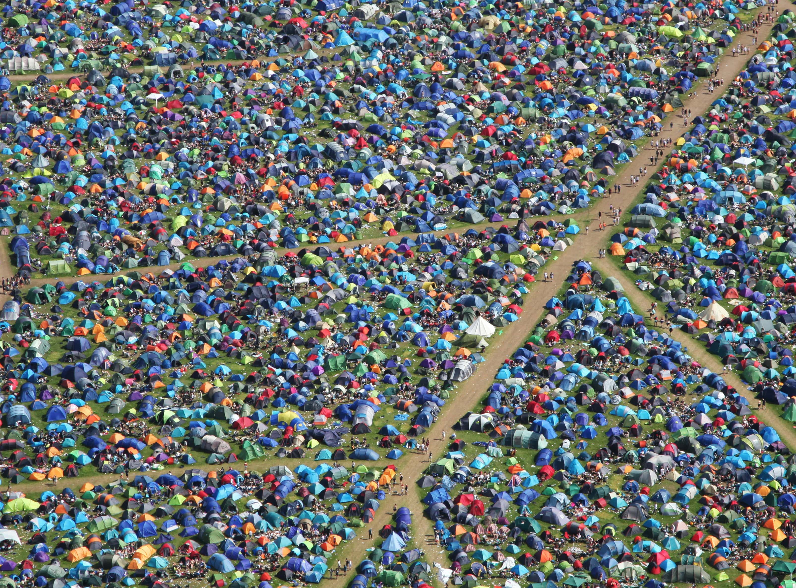 An image of a Glastonbury campsite from the sky. Covered in tents with people walking about the paths