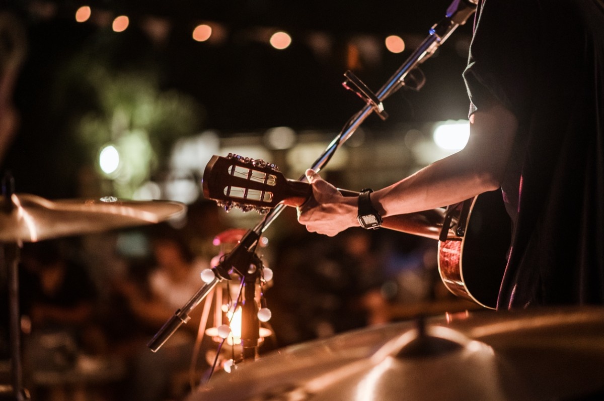 A man with a guitar performing to a festival crowd 