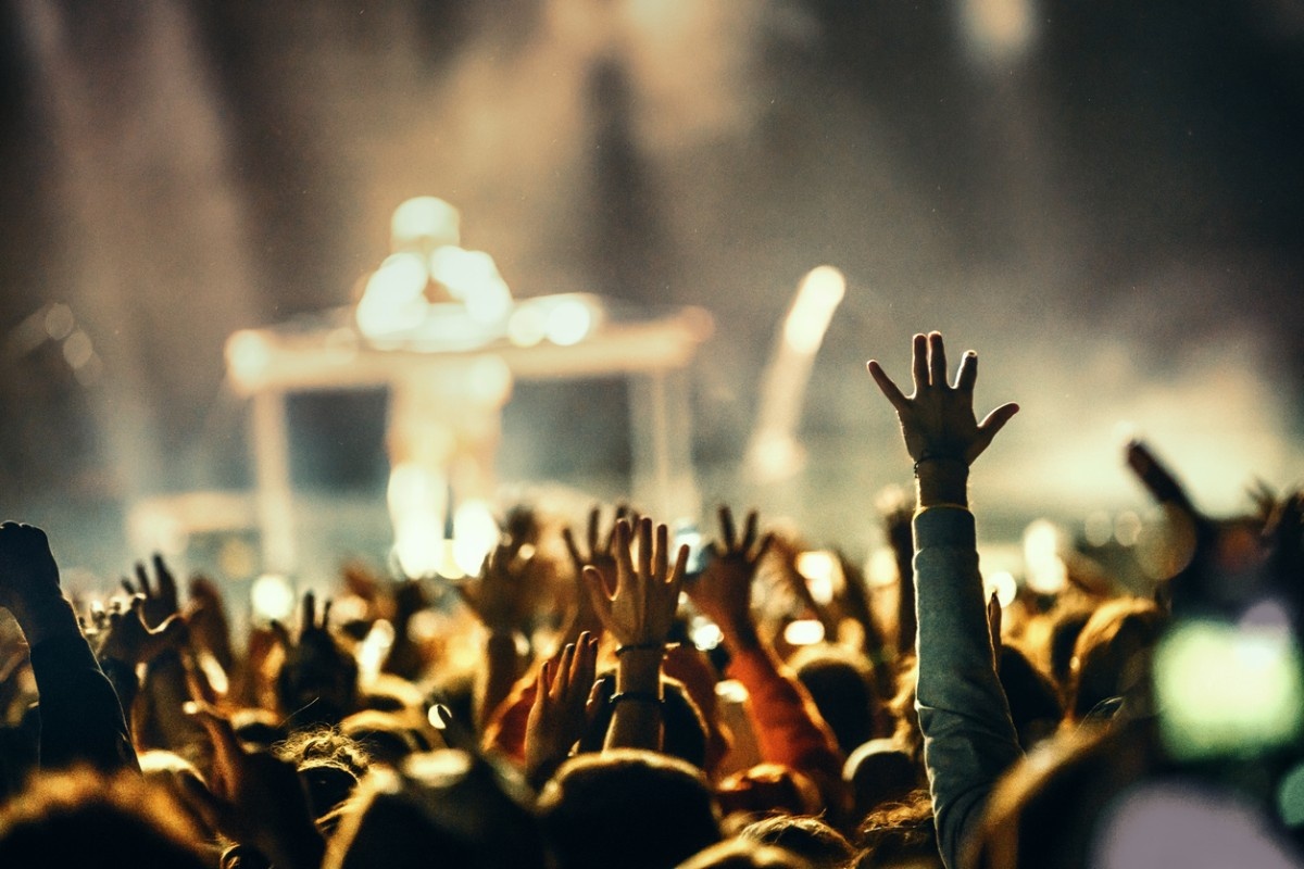 A crowd with their hands in the air whilst a DJ performs on stage at We Out Here Festival 