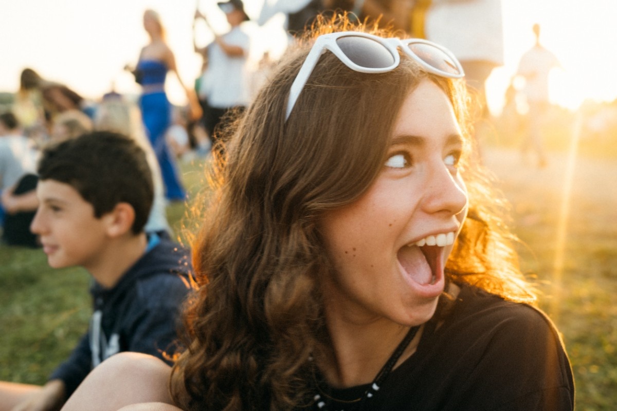 A girl sat in the sun at the festival, happy 