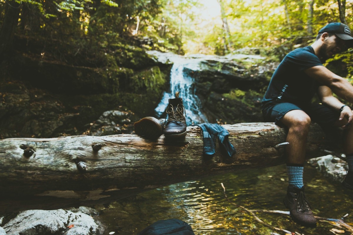 A person with their hiking boots and socks on a log