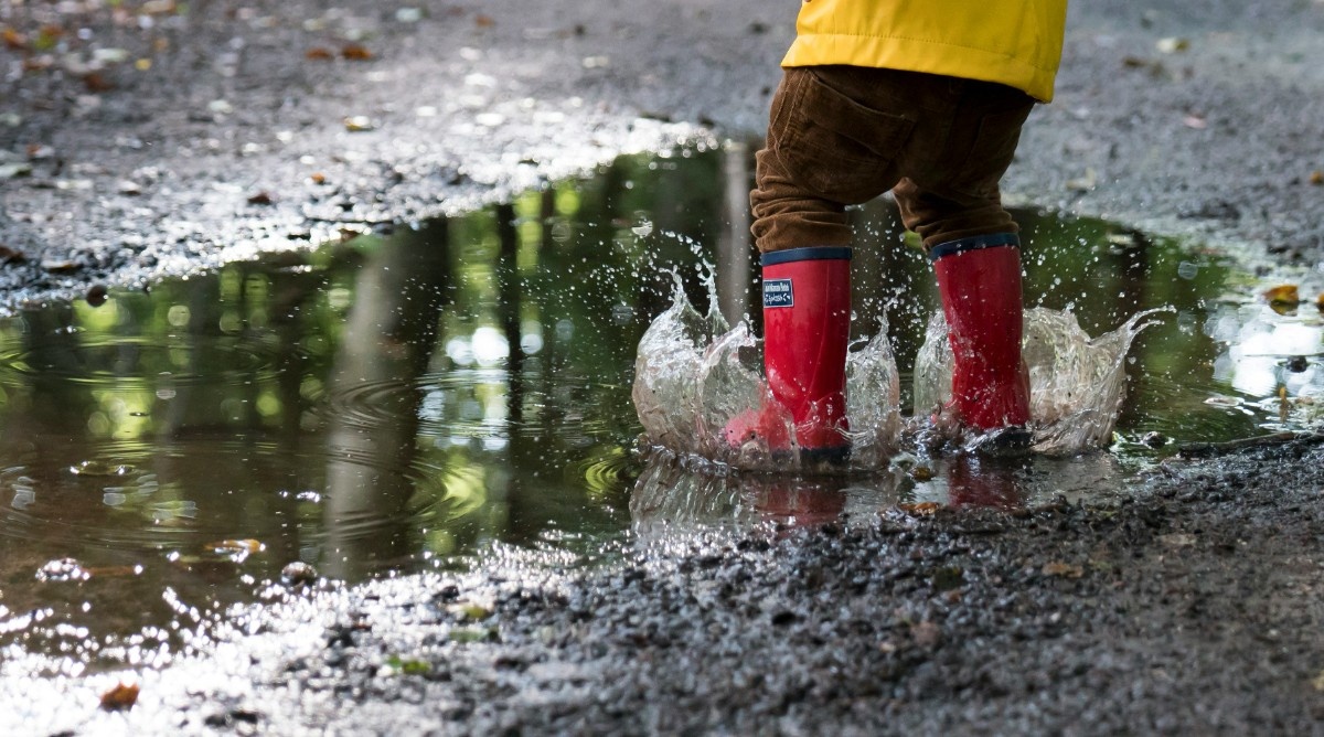 A kid jumping in a puddle on a rainy day 