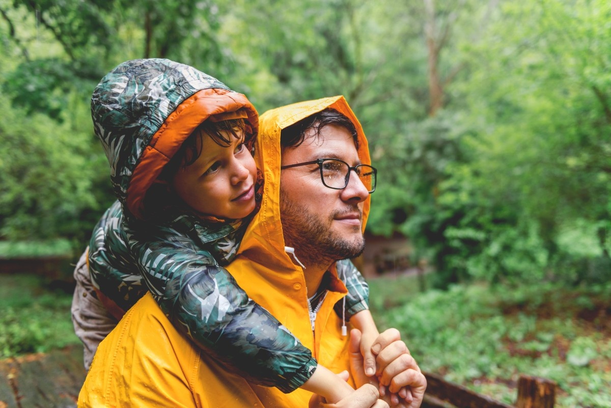 A man and his child walking through a woodland in the rain 