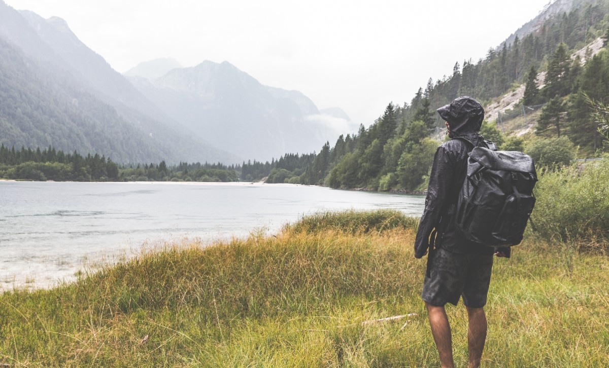 A man looking out to a lake in the rain 