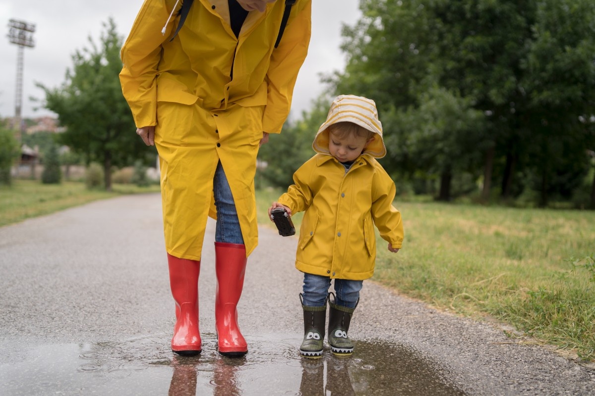 A mother and child jumping in puddles on a rainy day 