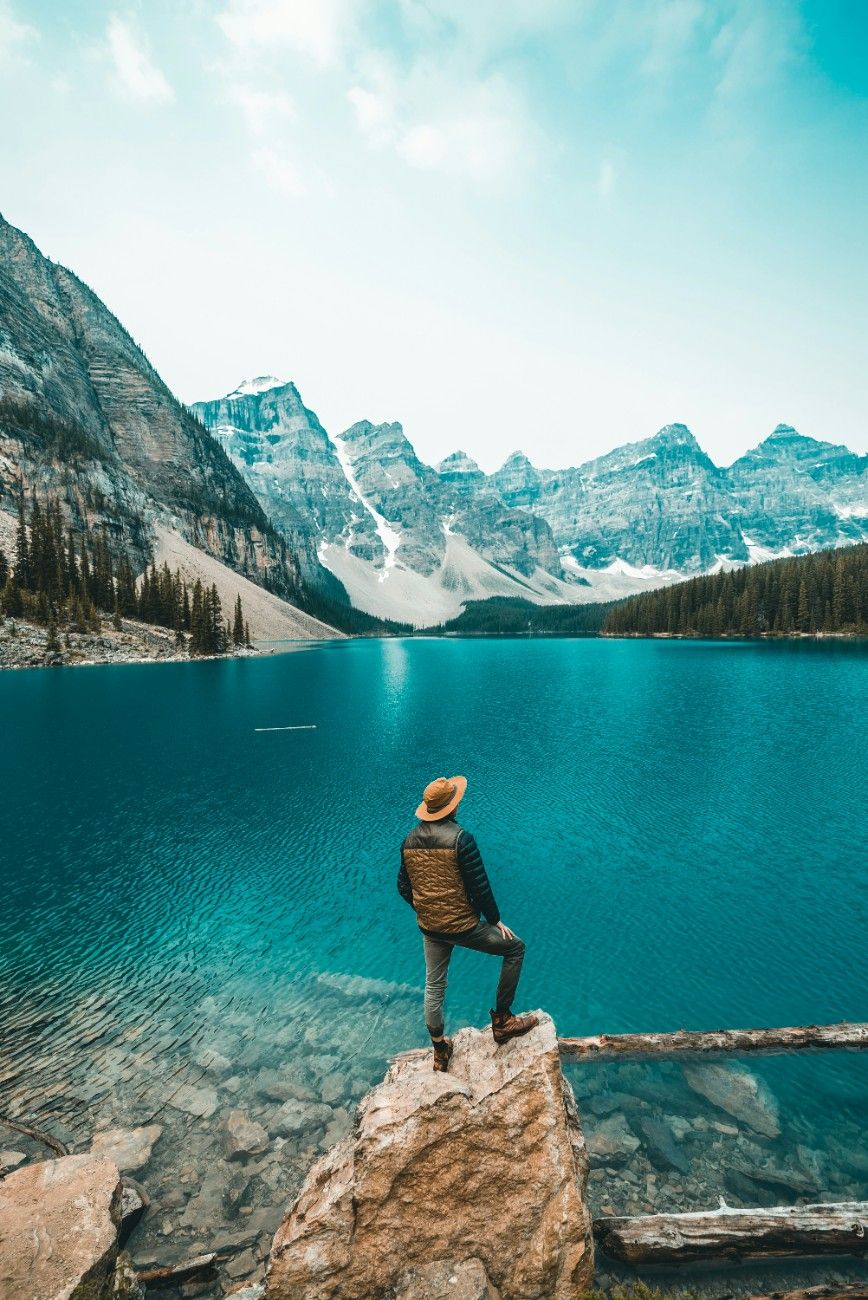 An man stood by Lake Moraine in the summertime in Banff National Park