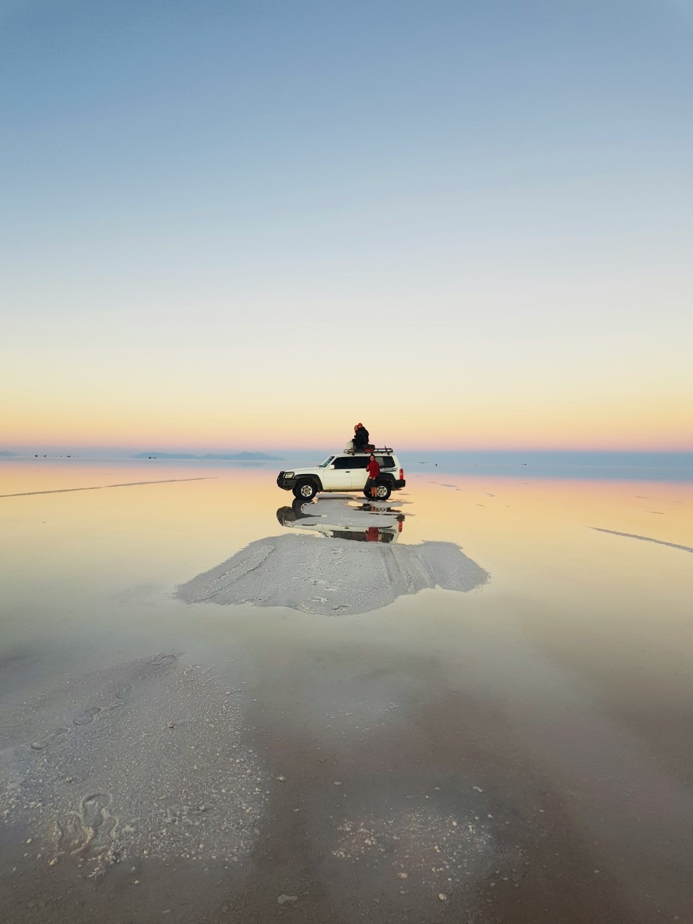 People sat on a truck on the Salar de Uyuni salt flats in Bolivia