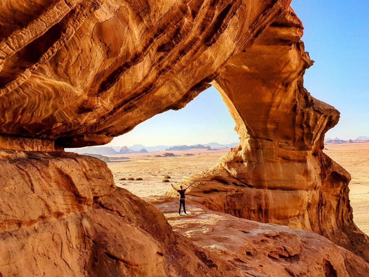 A person under a rock formation in Wadi Rum desert 