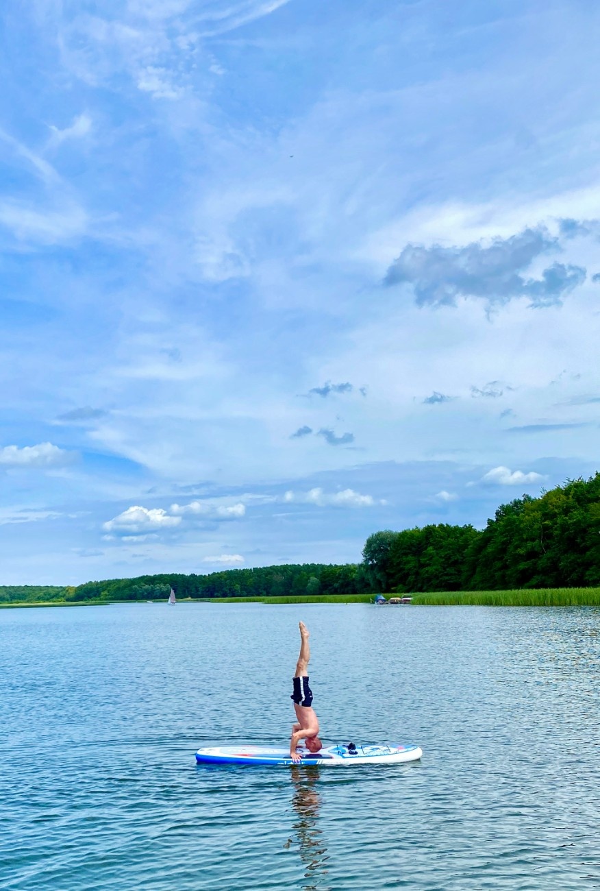 A man doing a headstand on a paddleboard