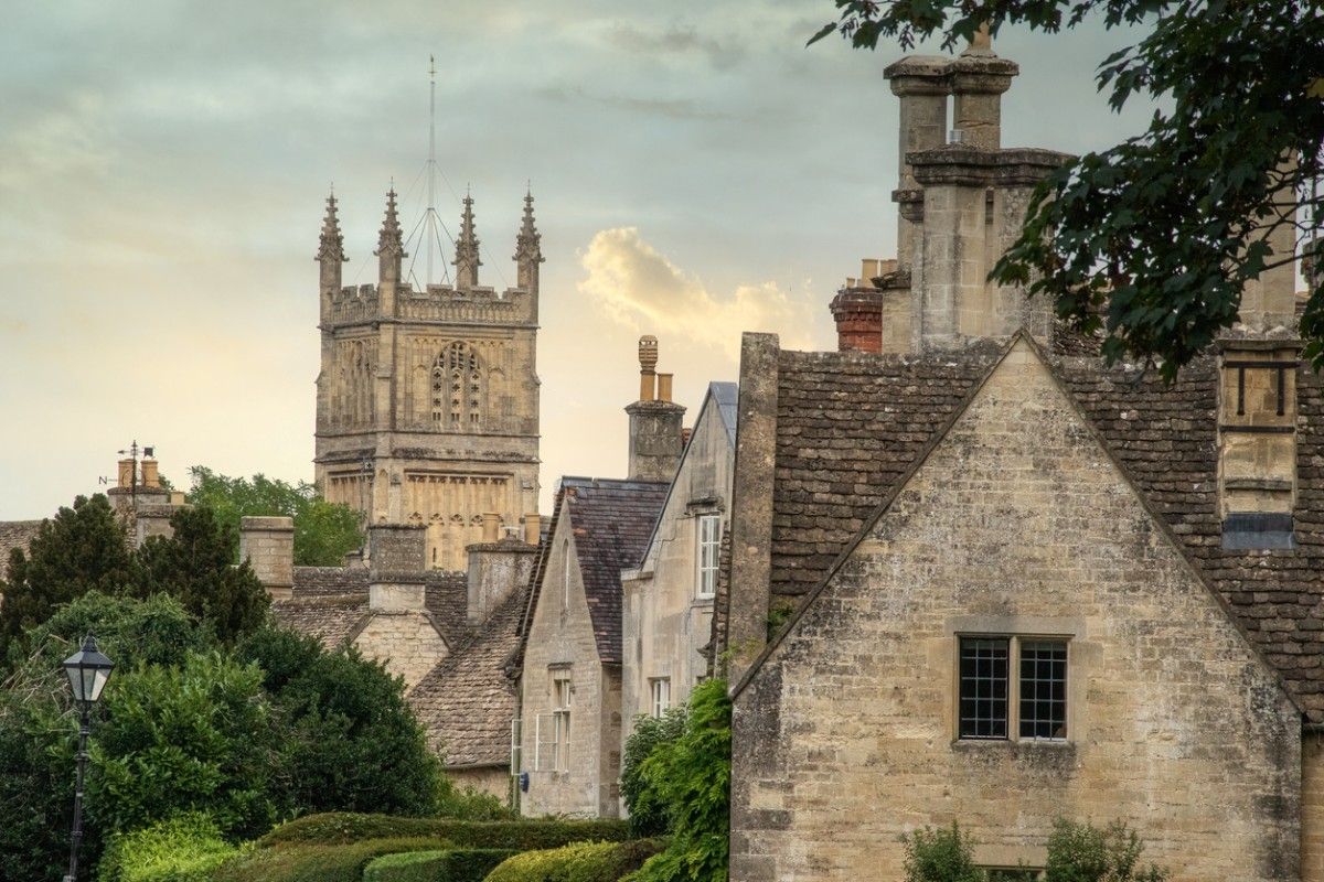 An image of some cottages in Cirencester with Cirencester Abbey in the distance 