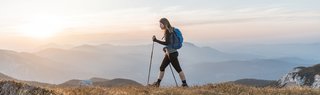 Young woman with a backpack hiking in the mountains. Exploring in the nature, enjoying the view.